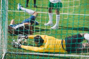 back view of goalkeeper catching ball during soccer game on pitch