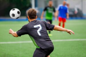 Football player in the soccer field chases the ball in a game action.